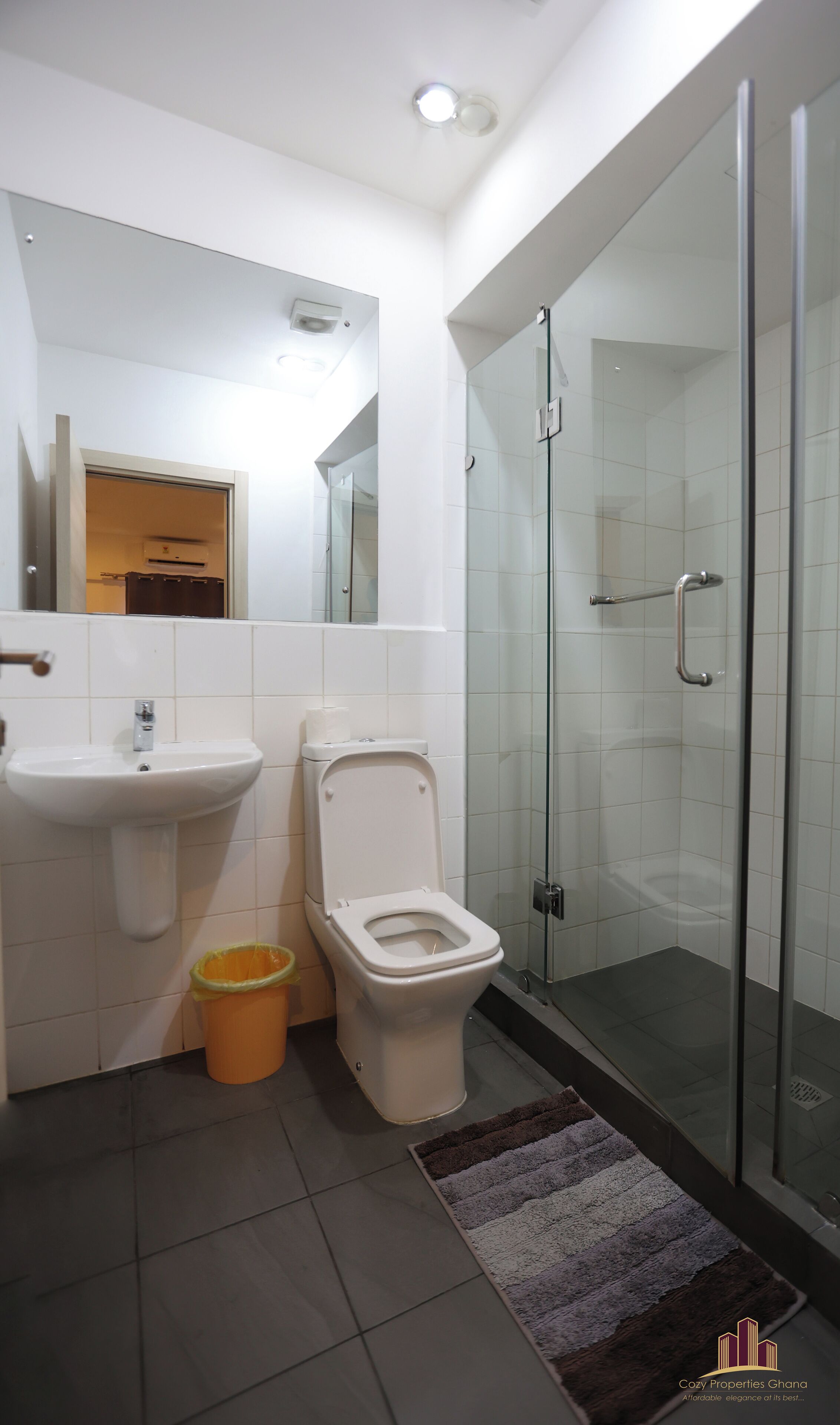 A modern bathroom with a glass shower enclosure, a sink, and a toilet.