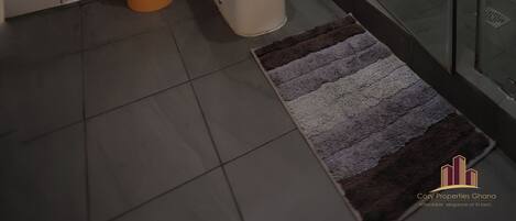 A modern bathroom with a glass shower enclosure, a sink, and a toilet.