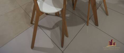 A compact kitchen with a refrigerator, microwave, oven, and washing machine. There is a round table with four chairs.