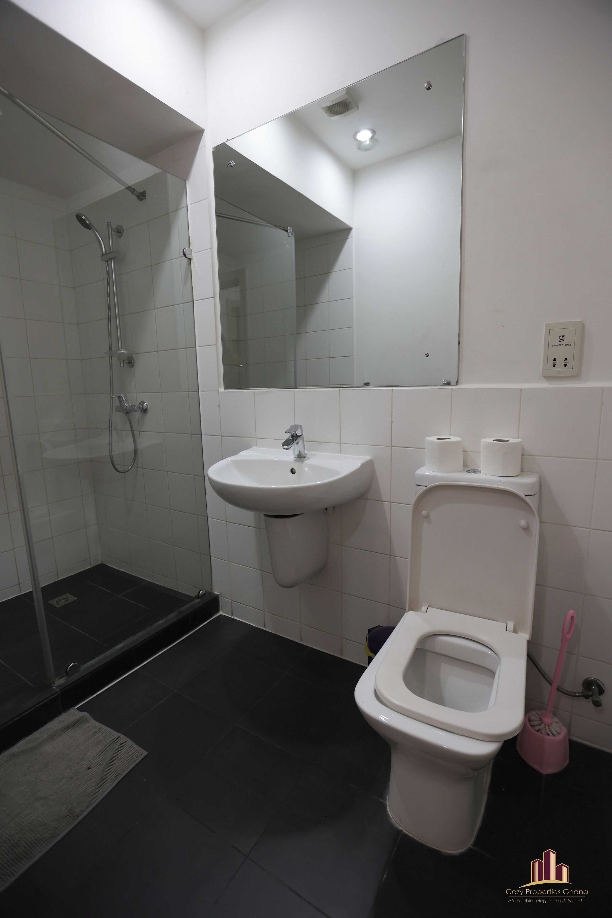 Un baño con ducha, lavabo, inodoro y espejo.