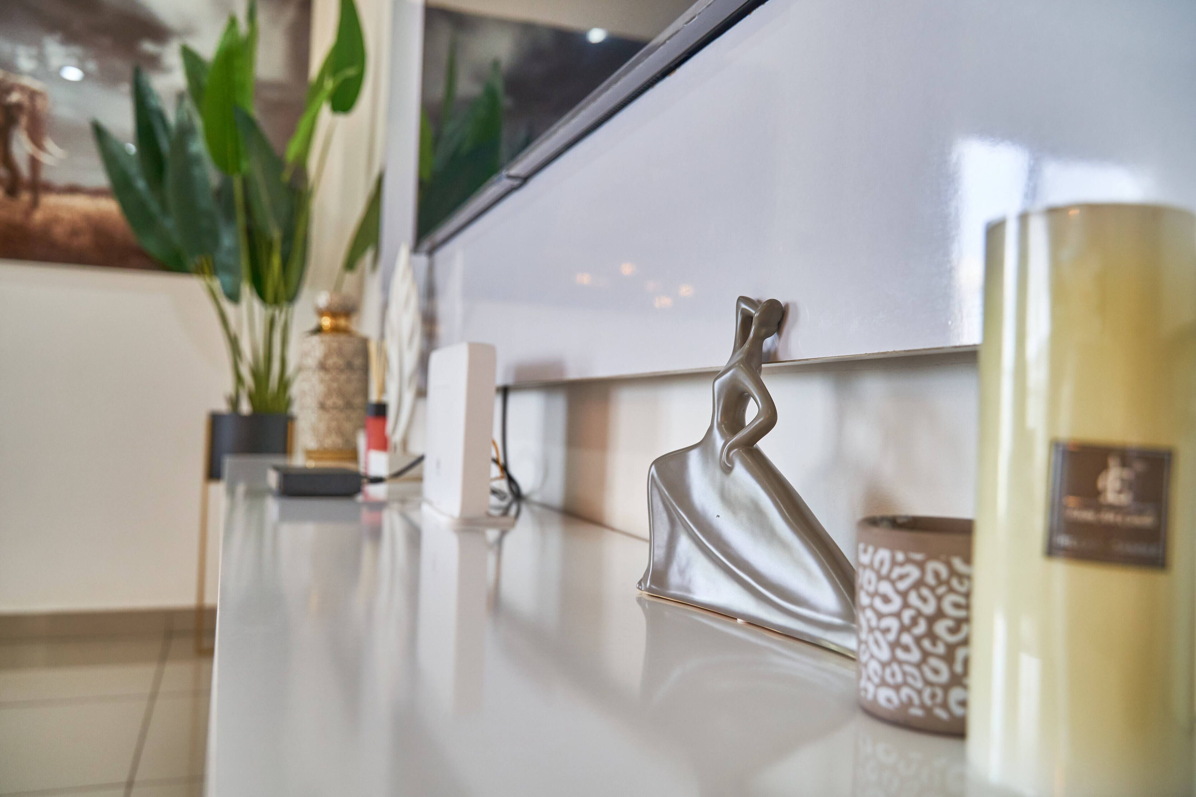 A modern kitchen with a white countertop, a decorative metal sculpture, and a patterned candle holder.