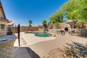 Enjoy a backyard with a pool, barbecue area, and comfortable seating amidst lush greenery.