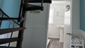 A spiral staircase leading to an upper floor, with a view of a bathroom and a white door with a decorative metal handle. - 4 Blocks to Beach, Linens Provided (Cape May)