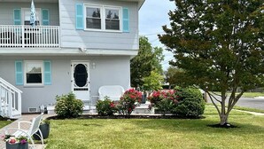A two-story house with a front porch, a small garden with red flowers, and a tree. - 4 Blocks to Beach, Linens Provided (Cape May)