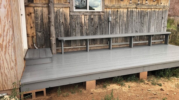 A rustic wooden building with a metal roof, a bench, and a window with hanging lights. - Newly Restored Vintage Cabin near Bryce, Grand Staircase. Great views! (Henrieville)
