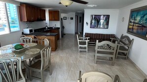 Uma sala ampla com uma mesa de jantar, cadeiras, um sofá e um ventilador de teto.