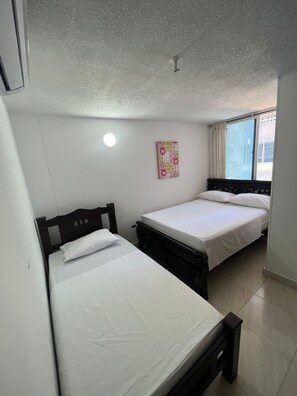 Ein Zimmer mit zwei Betten, einem Vorhangfenster und einer Deckenleuchte.