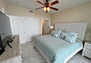 A bedroom with a bed, a ceiling fan, a nightstand, and a dresser.