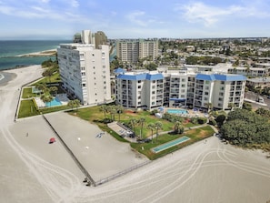 Een strandhotel met meerdere gebouwen, een zwembad en een strand.