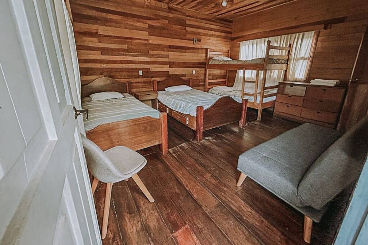 Eine Holzhütte mit Holzwänden und -böden, Stockbetten, einem Schreibtisch und einem Stuhl.
