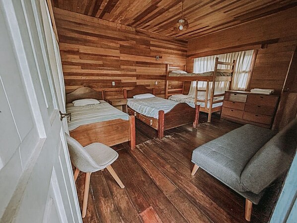 Una cabaña con paredes y suelos de madera, camas literas, un escritorio y una silla.