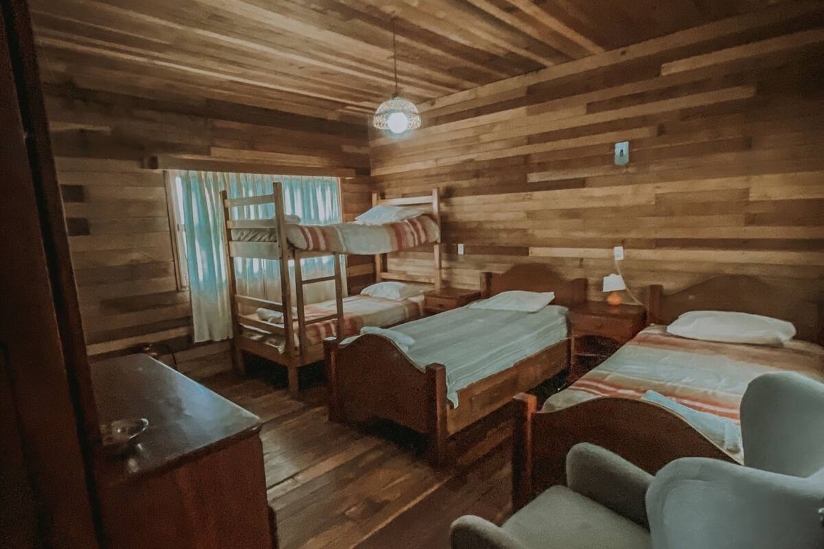 Ein holzgetäfeltes Zimmer im Blockhausstil mit Etagenbetten, einem Schreibtisch und einem Stuhl.