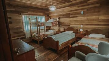 Ein holzgetäfeltes Zimmer im Blockhausstil mit Etagenbetten, einem Schreibtisch und einem Stuhl.
