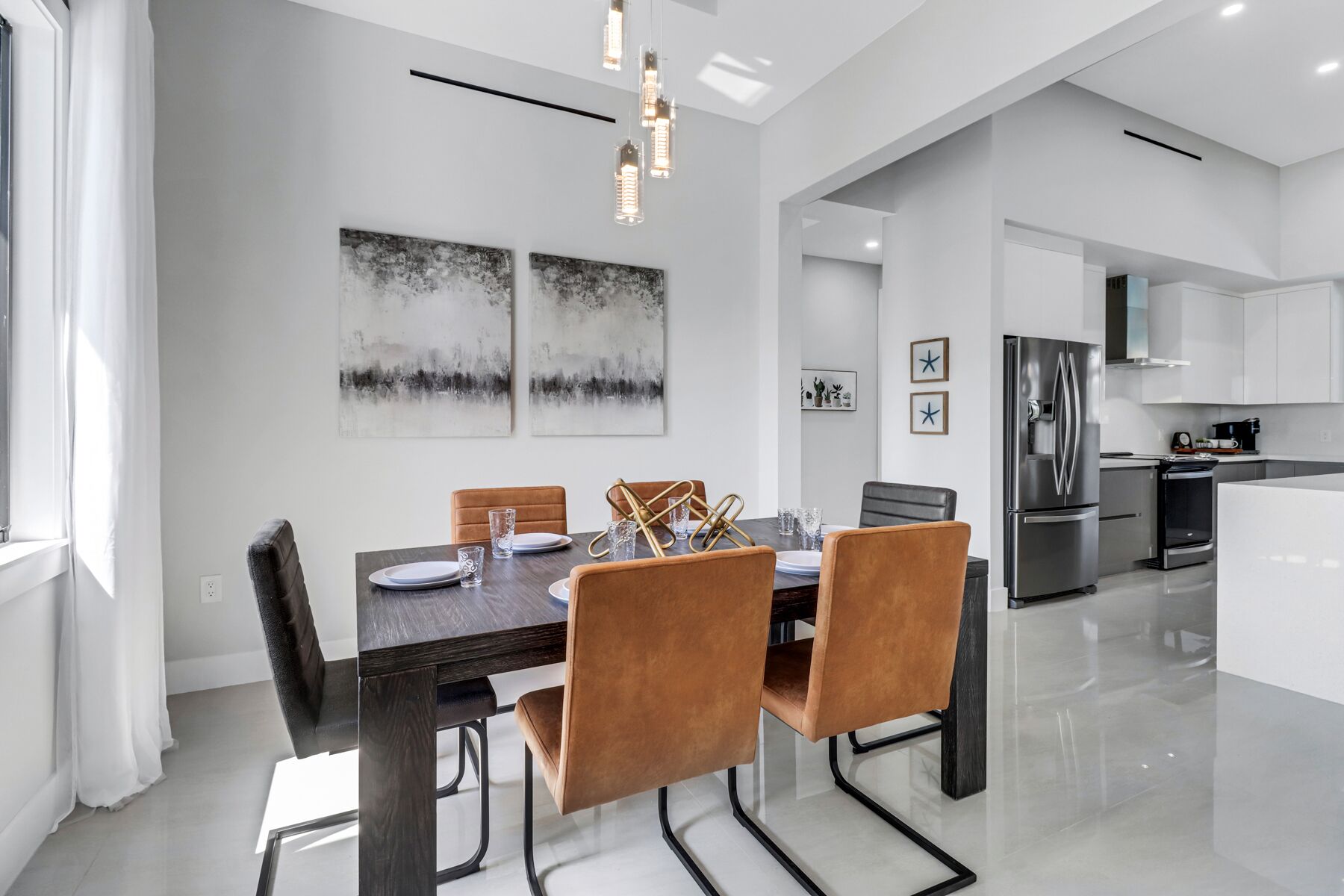 A modern dining area with a dark wooden table, brown upholstered chairs, and two abstract paintings on the wall.