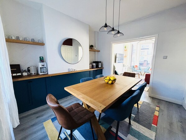 Een moderne keuken met een houten tafel, blauwe stoelen en een schaal met citroenen.