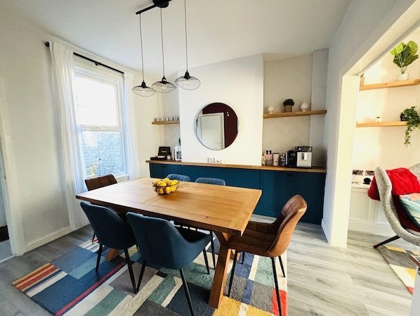 Une cuisine moderne avec une table et des chaises en bois, un miroir rond et un four encastré.