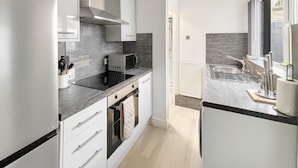 Een moderne keuken met witte kasten, een zwart aanrecht en een inbouw-magnetron.