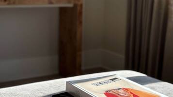 Una pila de libros sobre una mesa, con una lámpara al fondo.