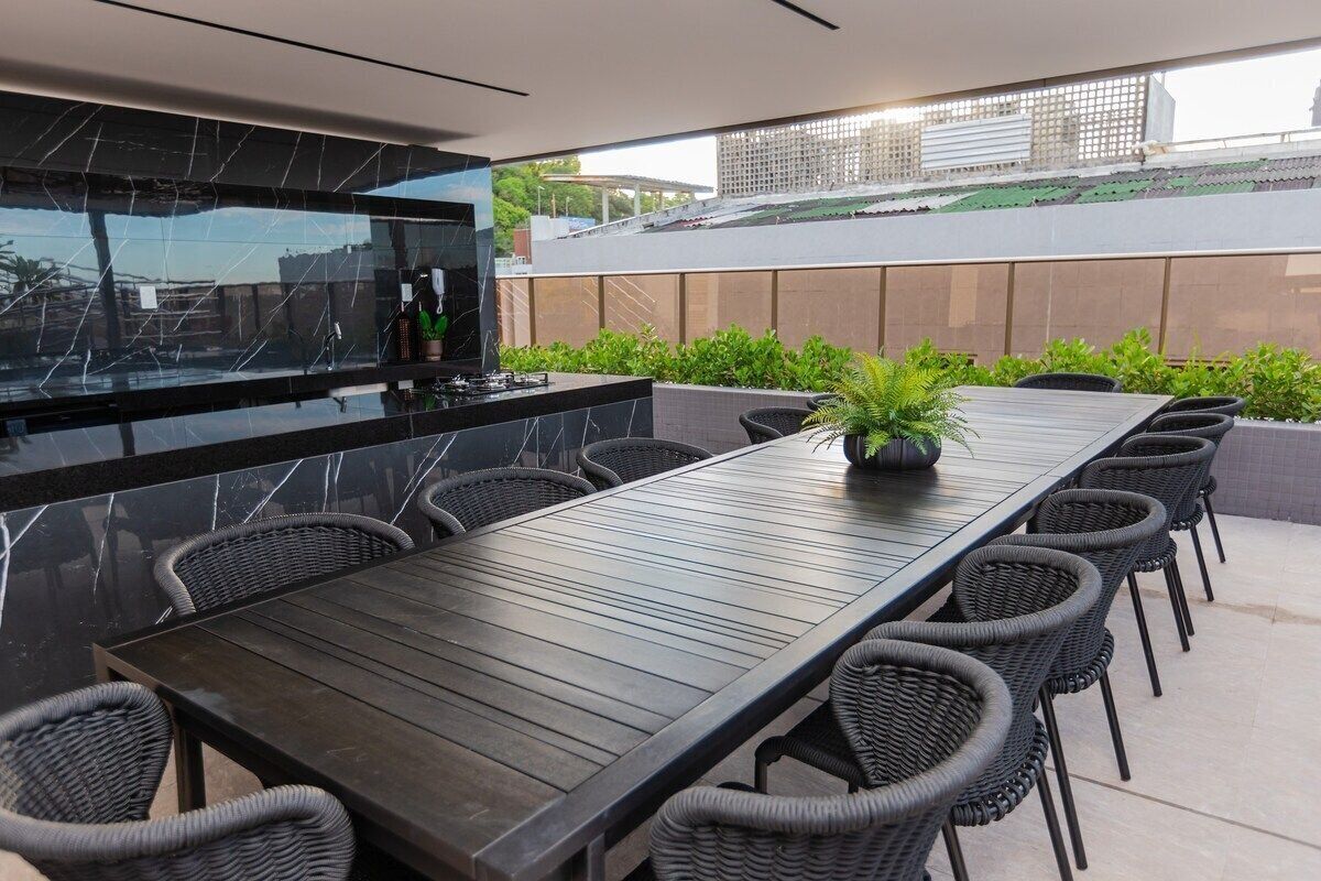 Een moderne eethoek buiten, met een lange tafel, rieten stoelen en een potplant.