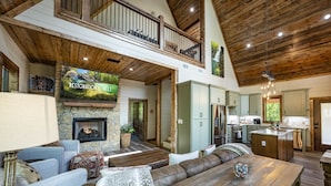 A spacious living area with a fireplace, a large sofa, a dining table, and a kitchen area.