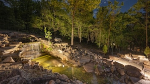 A natural setting with a small waterfall, rocks, and trees.