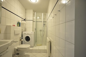Ein kleines Badezimmer mit Toilette, Waschmaschine und einer Duschkabine.