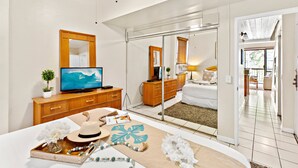 Een moderne hotelkamer met een groot bed, een televisie, een houten dressoir en een schuifdeur naar een balkon.