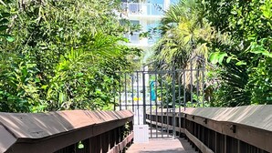 A wooden bridge with railings, surrounded by dense greenery and trees. - St. Nicole Condo in Pelican Bay, Naples, Florida with Gorgeous Gulf Views (Naples)