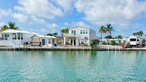 A waterfront property with multiple buildings, including a house with a balcony and a covered area. - Endless Water Views - Venture Out 526 (Cudjoe Key)