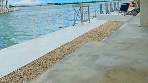 A waterfront promenade with a concrete walkway, seating area, and a view of the water. - Endless Water Views - Venture Out 526 (Cudjoe Key)