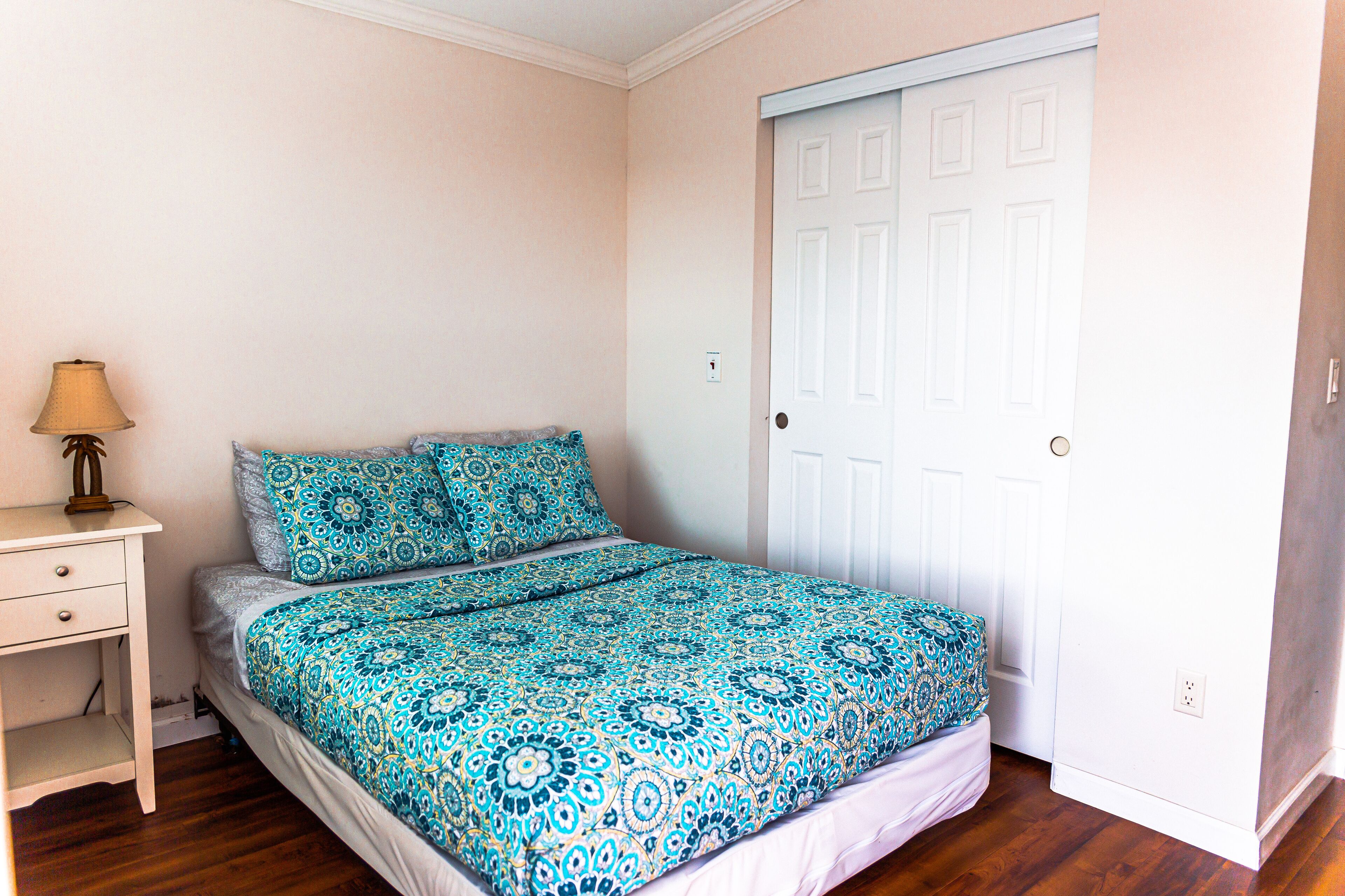 A bedroom with a bed, a nightstand, and a door.