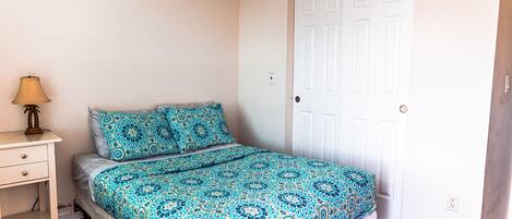 A bedroom with a bed, a nightstand, and a door.