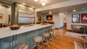 Una cocina moderna con una isla grande, taburetes de bar y un refrigerador de acero inoxidable.
