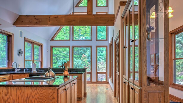 Una cocina amplia con grandes ventanales, armarios de madera y una isla central.
