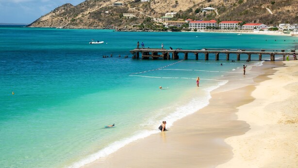 A beach with a pier extending into the water, a sandy shore, and buildings in the background. - 2 bedroom Apartment Residence Catalina (Grand-Case)