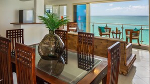 A dining area with a glass table, wooden chairs, and a view of the ocean. - 2 bedroom Apartment Residence Catalina (Grand-Case)
