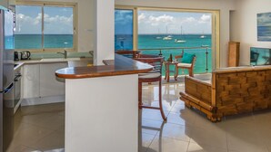 A modern kitchen with a large window overlooking the sea, a wooden bar counter, and a dining area with chairs and a table. - 2 bedroom Apartment Residence Catalina (Grand-Case)