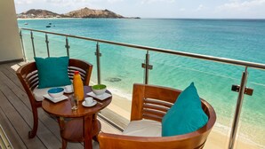 A wooden deck with a table set for two, overlooking a turquoise sea with boats and a distant hill. - 2 bedroom Apartment Residence Catalina (Grand-Case)