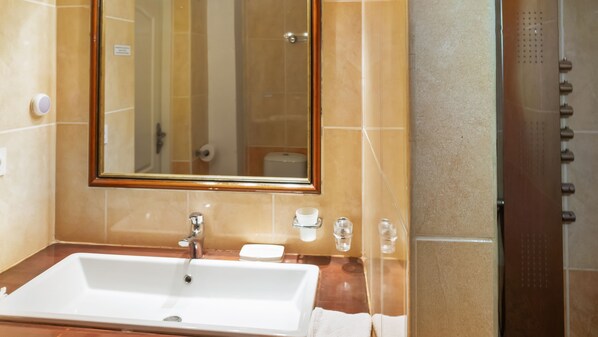 Ein Badezimmer mit großem Spiegel, Waschbecken und Duschbereich.