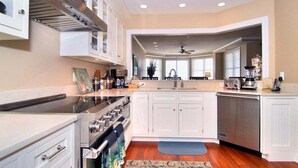 A modern kitchen with white cabinetry, a built-in oven, a dishwasher, and a large window.