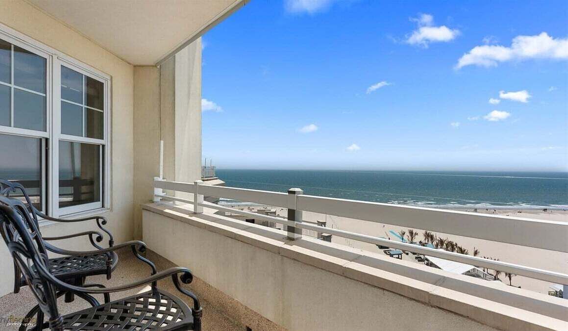 Een balkon met uitzicht op zee, een raam en een bank.