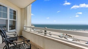 Un balcon avec vue sur l’océan, une fenêtre et un banc.