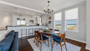Una cocina moderna con comedor, ventanas amplias y vista a la playa.
