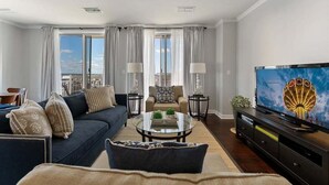 Una sala de estar con sofá, mesa de centro, televisor y vistas de la ciudad.