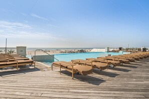 A wooden deck with lounge chairs and a pool.