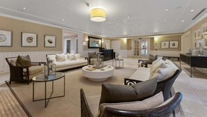 Un hall d’hôtel spacieux, aménagé avec un canapé, des fauteuils, une table basse et un téléviseur.