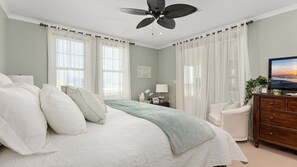 A bedroom with a bed, a nightstand, a dresser, a television, and a ceiling fan. - Residence 509 at The Grand (Wildwood)