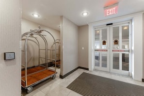 A hotel entrance with an exit sign, a push-to-open emergency door, and a luggage cart. - Residence 703 at The Grand (Wildwood)