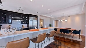 Eine moderne Küche mit dunklen Schränken, einem Edelstahlkühlschrank und einer Bar mit Sitzgelegenheiten.