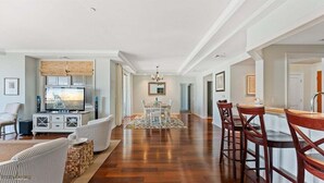 A spacious living area with a dining table, chairs, a fireplace, and a television. - Residence 308 at The Grand (Wildwood)